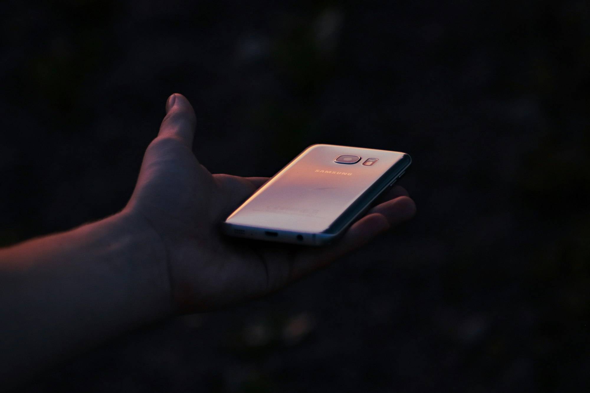 Una mano sosteniendo un móvil a la luz del atardecer